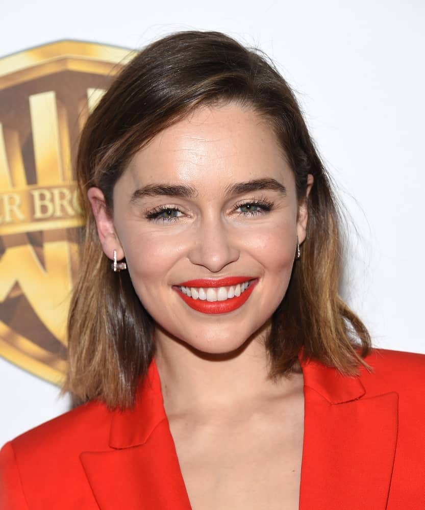 Emilia Clarke with a straight bob hair style arrives to CinemaCon 2016: Warner Bros. "The Big Picture". Wearing a low-cut orange red coat, she looks very classy and sexy.