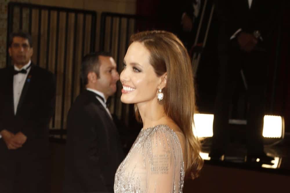 Angelina Jolie flashed her beautiful smile at the 86th Annual Academy Awards at Hollywood & Highland Center on March 2, 2014 in Los Angeles, California. She wore a lovely sheer dress that she paired with her long and loose brunette hairstyle tucked behind her ear.