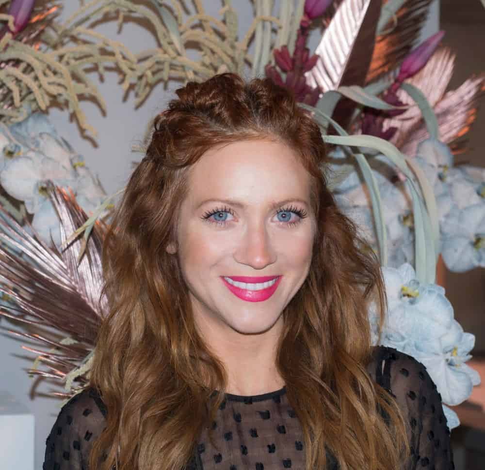 On February 10, 2018, actress Brittany Snow attended the Alice McCall Fall/Winter 2018 runway show during New York Fashion Week at Industria, Manhattan. She wore a black sheer dress with her curly and loose tousled long brunette half-up hairstyle incorporated with braids.
