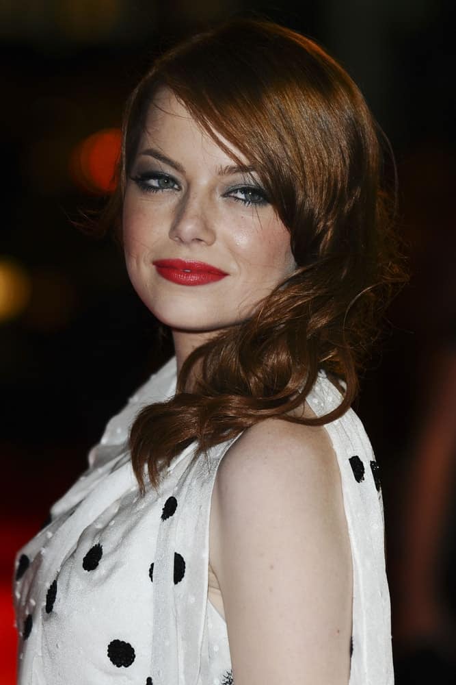 On May 10, 2011, Emma Stone was at the premiere of 'The Help' at the Curzon Mayfair in London. She wore a lovely white polka-dotted dress that she paired with a side-swept red hairstyle with tight curls.