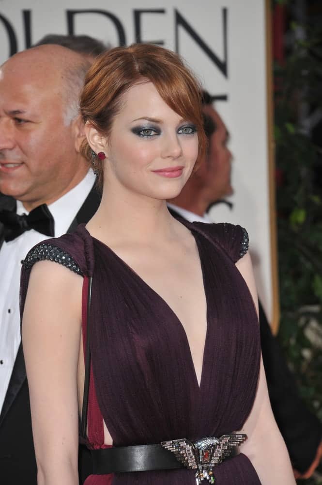 Emma Stone attended the 69th Golden Globe Awards at the Beverly Hilton Hotel on January 15, 2012 in Beverly Hills, CA. She was quite fashionable with her dress, accessories and low bun hairstyle with loose and long side-swept bangs.