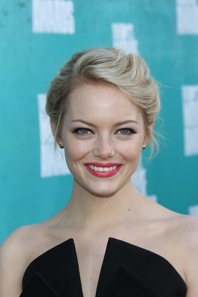 Emma Stone was at the 2012 MTV Movie Awards Arrivals held at the Gibson Amphitheater in Universal City, CA on June 3, 2012. She wore a stunning black dress that paired well with her bold lips and messy upstyle bun hairstyle with a blond hue.