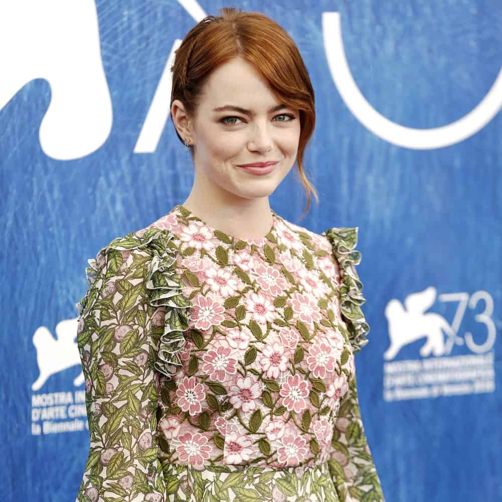 Actress Emma Stone paired her sweet and lovely floral dress with a side-swept bun hairstyle incorporated with long and loose bangs as well as a single braid at the photo-call of 'La La Land' during the 73rd Venice Film Festival on August 31, 2016 in Venice, Italy.