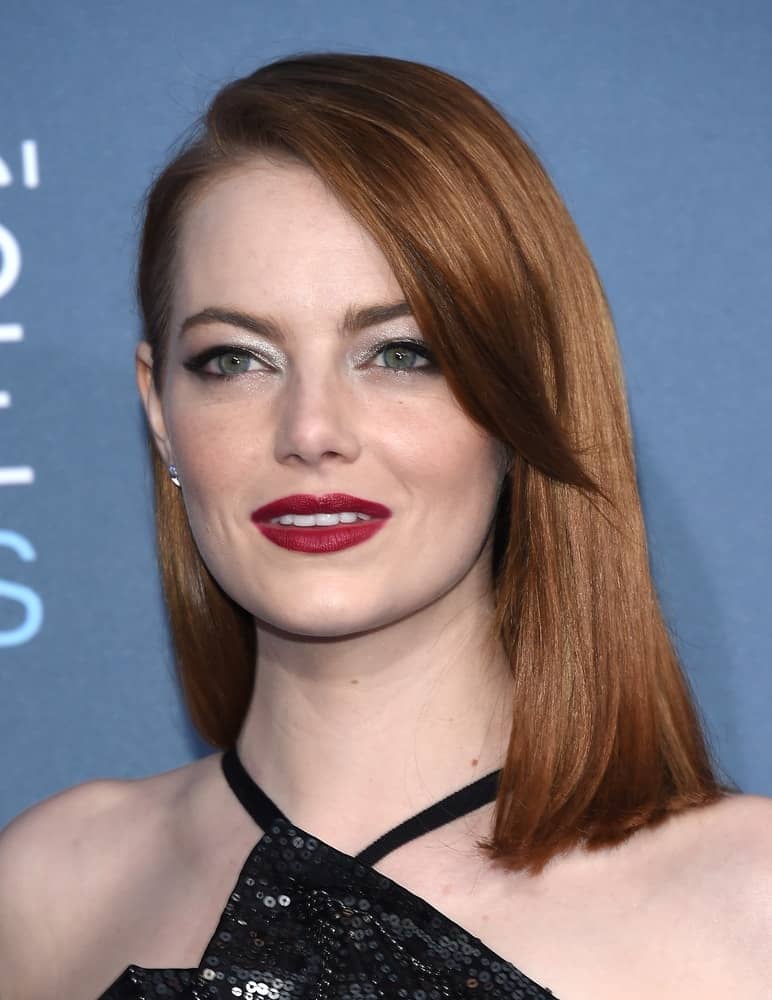 Emma Stone's stunning and sexy black dress emphasized her lovely neckline along her red layered straight hairstyle at the Critics' Choice Awards 2016 on December 11, 2016 in Hollywood, CA.