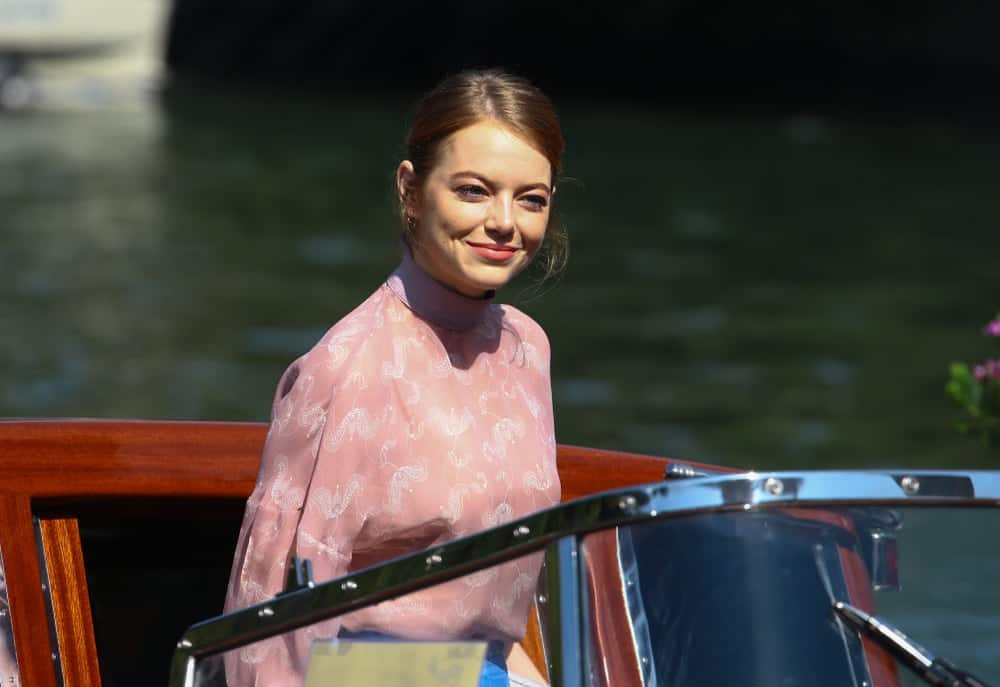 Emma Stone was seen during the 75th Venice Film Festival on August 30, 2018 in Venice, Italy. She was on a boat wearing a casual but lovely pink blouse and her hair was swept up into a slightly messy tight bun.