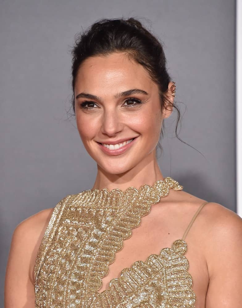 Gal Gadot attended the "Justice League" World Premiere on November 13, 2017 in Hollywood, CA. She came in an asymmetrical golden dress with her hair styled into a messy bun with loose tendrils.