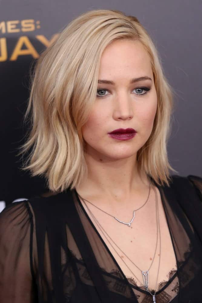Jennifer Lawrence went with bold lips and black sheer dress to go with her platinum blond side-swept wavy bob hairstyle at the premiere of "The Hunger Games: Mockingjay - Part 2" at AMC Lincoln Square on November 18, 2015 in New York City.