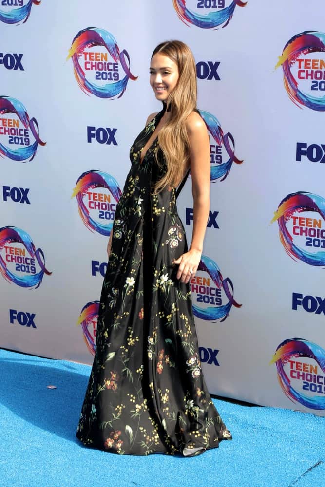 Jessica Alba wore a lovely long black floral dress with her long, wavy and layered brown hairstyle loose on her shoulders at the Teen Choice Awards 2019 at Hermosa Beach on August 11, 2019 in Hermosa Beach, CA.