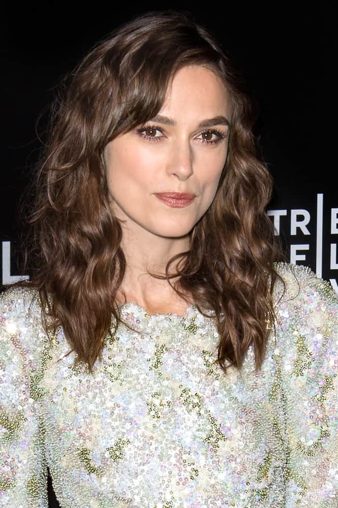 On April 26, 2014, actress Keira Knightley attended the closing night gala premiere of 'Begin Again' during the 2014 Tribeca Film Festival at BMCC Tribeca PAC. She wore a colorful sequined dress with her shoulder-length wavy layered hairstyle with a slight tousle.