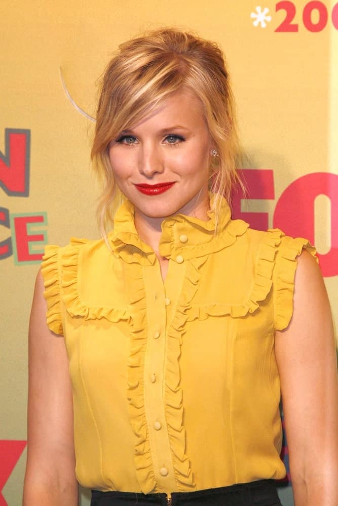 Kristen Bell had messy upstyle with side bangs and tendrils during the 2006 Teen Choice Awards at Gibson Amphitheatre on August 20, 2006. She completed the look with red lipstick and a yellow ruffle top.