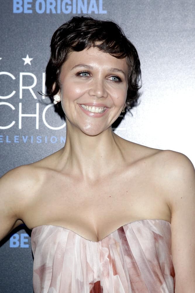 Maggie Gyllenhaal was at the 5th Annual Critics' Choice Television Awards at the Beverly Hilton Hotel on May 31, 2014 in Beverly Hills, CA. She paired her lovely beige strapless dress with a curly pixie hairstyle with side-swept short bangs.