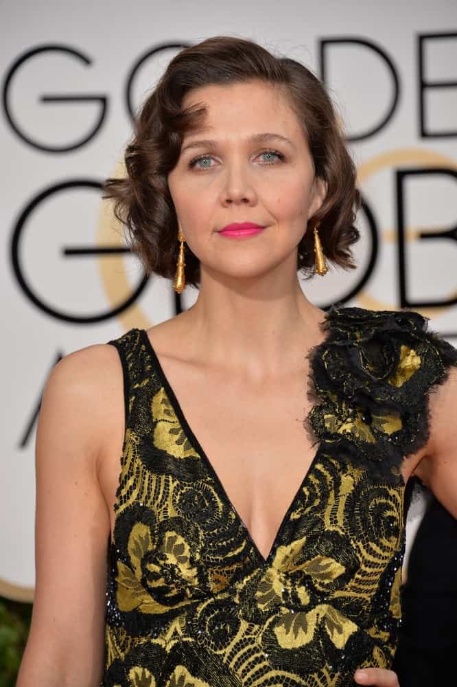 On January 10, 2016, Maggie Gyllenhaal attended the 73rd Annual Golden Globe Awards at the Beverly Hilton Hotel. She was stunning in a black and gold dress that she paired with her chin-length curly brunette hairstyle with layers.