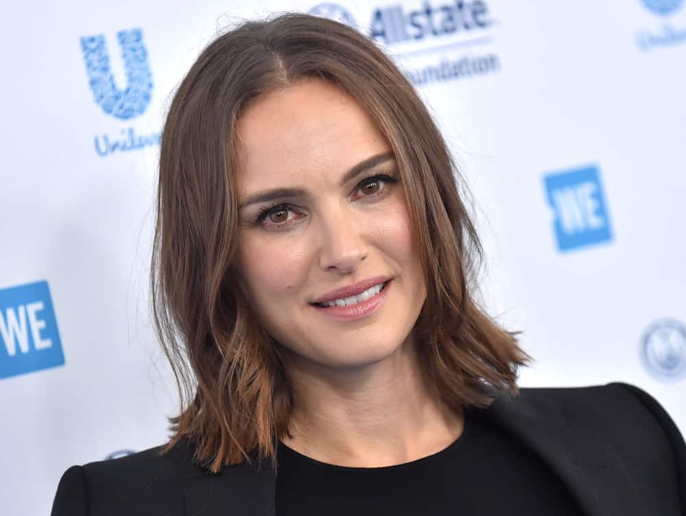 Natalie Portman was at the WE Day California 2019 on April 25, 2019 in Inglewood, CA. She came wearing a black smart casual outfit to match her simple make-up and loose layered bob hairstyle with a slight tousle and long side bangs.