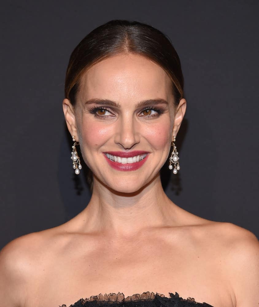 Natalie Portman's elegant make-up and earrings went perfectly well with her strapless black dress and slick highlighted bun hairstyle when she arrived for the ELLE Women in Hollywood on October 14, 2019 in Westwood, CA.