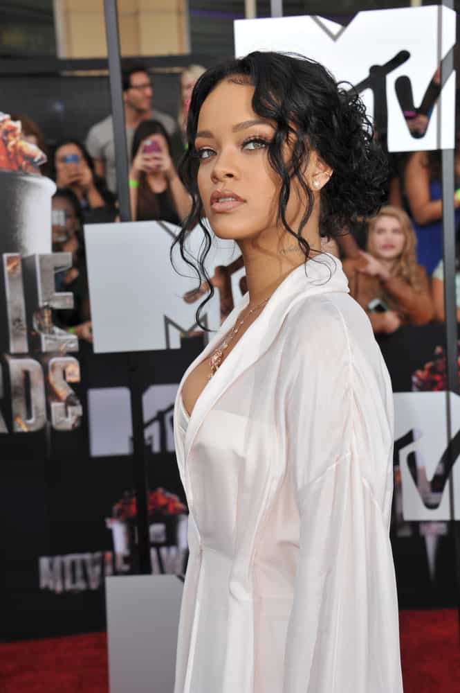 On April 13, 2014, Rihanna's long and curly raven hair was swept up into a messy low bun hairstyle with loose curly tendrils at the 2014 MTV Movie Awards at the Nokia Theatre LA Live.