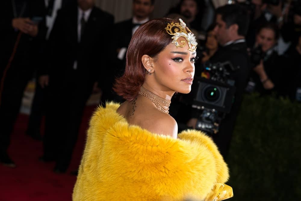 On May 04, 2015, Rihanna attended the 'China: Through The Looking Glass' Costume Institute Gala, held at the Metropolitan Museum of Art in New York City, New York. She wore a vintage yellow dress with fur to match her golden headdress on her slicked back reddish hairstyle.