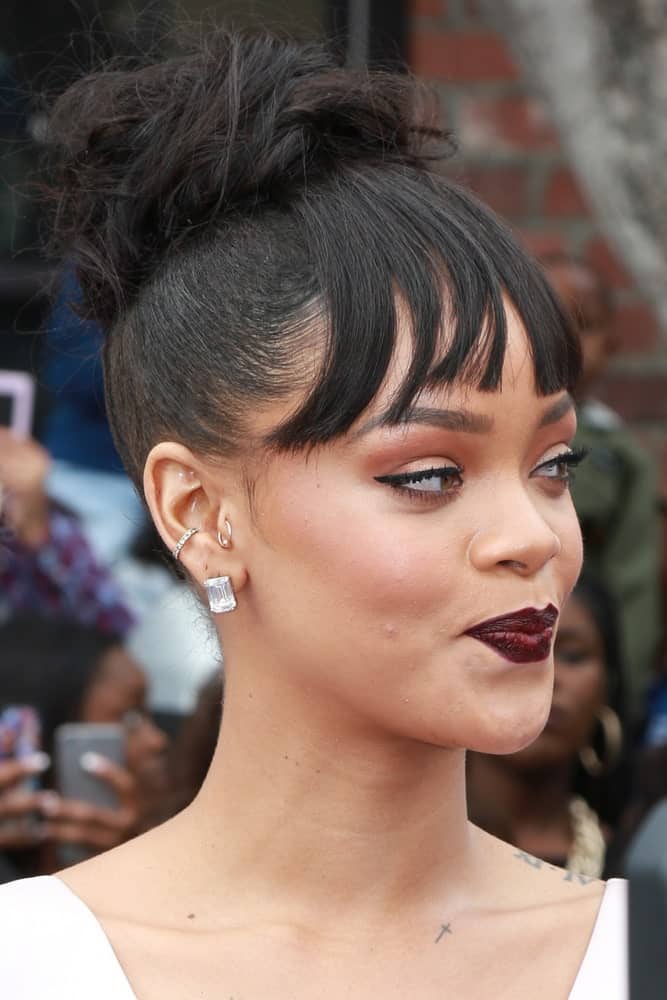 Rihanna's lovely dark lips matched well with her white outfit and top knot bun hairstyle with bangs at the "Home" Special Screening Red Carpet at the Village Theater on March 22, 2015 in Westwood, CA.