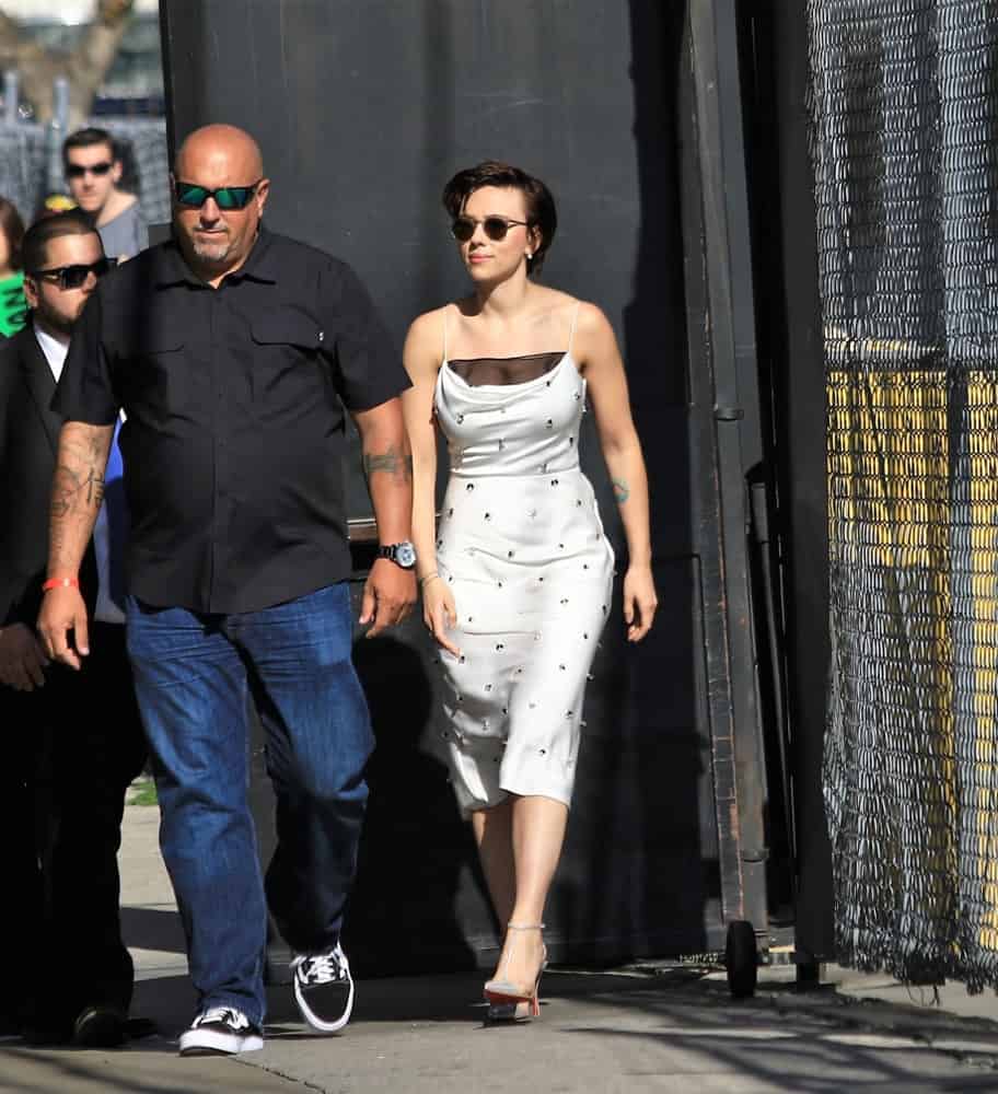 Actress Scarlett Johannson was seen walking to the Jimmy Kimmel studio during the Avengers week on Jimmy Kimmel Live! on April 24, 2018. She wore a white summer dress that she paired with cool sunglasses and a side-swept short dark hairstyle.