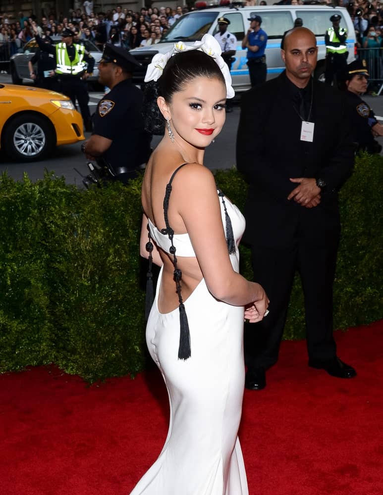 On May 04, 2015, Selena Gomez attended the 'China: Through The Looking Glass' Costume Institute Gala, held at the Metropolitan Museum of Art in New York City, New York. She paired her white dress with a slick bun hairstyle decorated with white flowers.