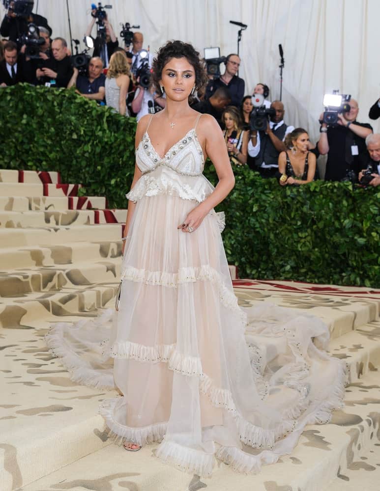 On May 7, 2018, Selena Gomez was at the Metropolitan Museum of Art Costume Institute Gala: "Heavenly Bodies: Fashion and the Catholic Imagination. She wore a beautiful long dress and paired it with a short and curly loose half up hairstyle.