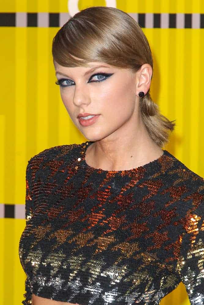 Taylor Swift looking all cool and trendy in her mid-rib outfit at the 2015 MTV Video Music Awards. She complemented it with a low ponytail bun and side-swept bangs.