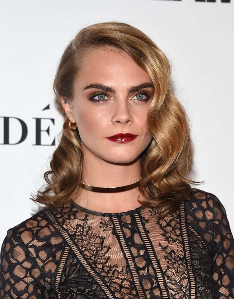 Cara Delevingne flaunted her famous eye brows with her black sheer outfit and side-swept sandy blond hairstyle incorporated with vintage curls at the Glamour Celebrates Women of the Year Awards 2016 on November 14, 2016 in Hollywood, CA.