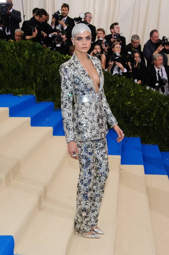 Cara Delevingne attended the 2017 Metropolitan Museum of Art Costume Institute Gala at the Metropolitan Museum of Art in New York, NY on May 1st, 2017. She went with a silvery and glittery suit to pair with her silver shoes and slick metallic pixie hairstyle.