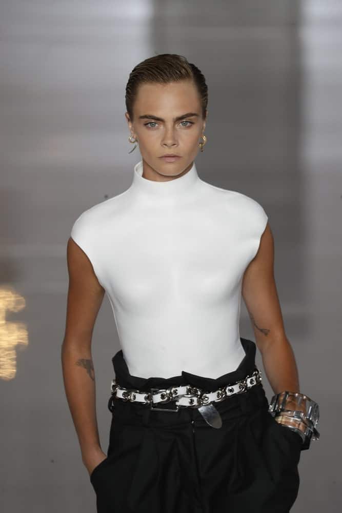 Model and actress Cara Delevingne walked the runway during the Balmain show as part of the Paris Fashion Week Women's wear Spring/Summer 2019 on September 28, 2018 in Paris, France. Her was styled to a slick side-parted finish with a dark brown tone.