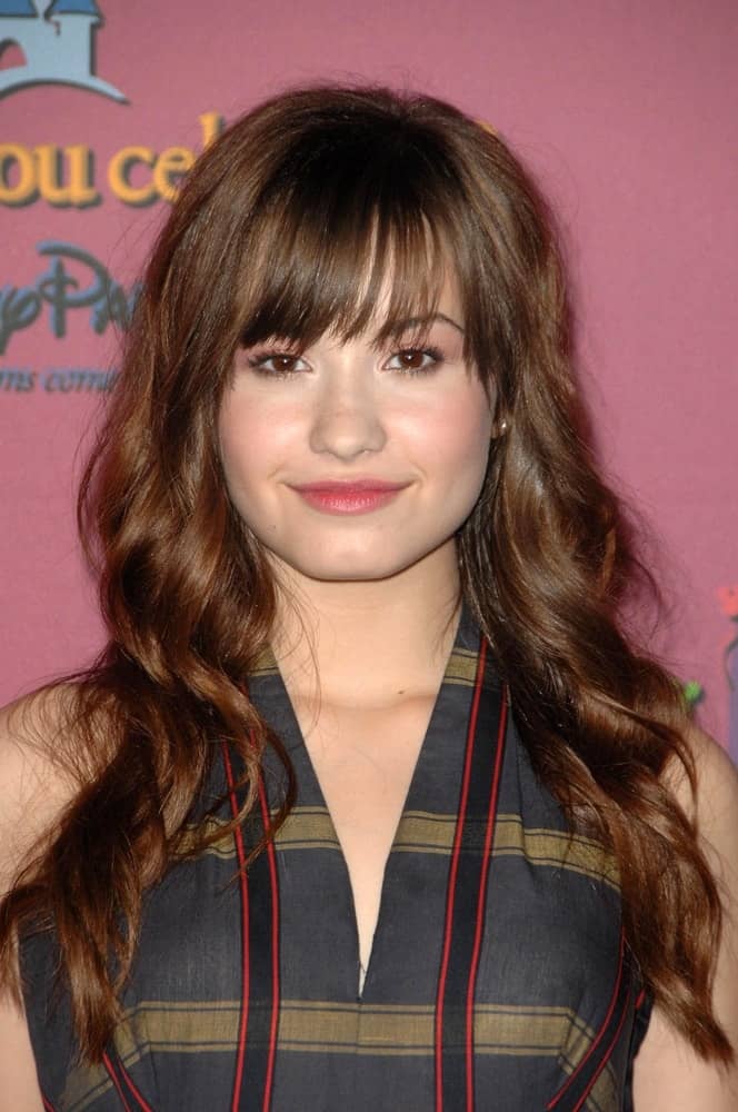 Demi Lovato attended the Miley Cyrus Sweet 16 Birthday Party and Concert held at the Disneyland Resort in Anaheim, CA on October 05, 2008.  She wore a patterned dress that paired quite well with her long and tousled dark brown hairstyle with blunt bangs and waves.