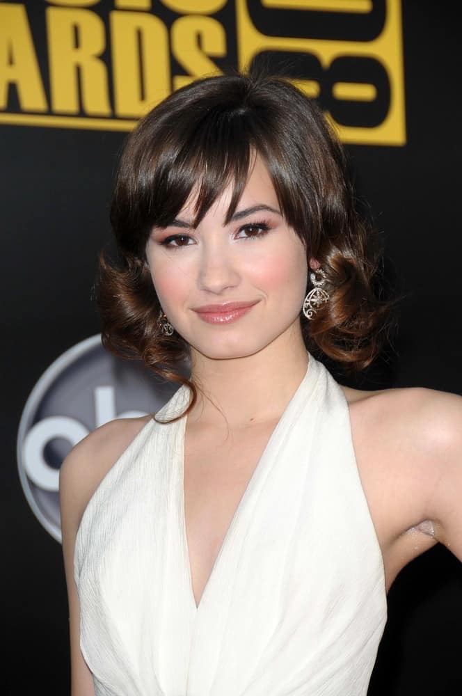 Demi Lovato wore a white dress with her curly shoulder-length hairstyle with highlights and bangs at the 2008 American Music Awards held at the Nokia Theatre in Los Angeles, CA on November 23, 2008.
