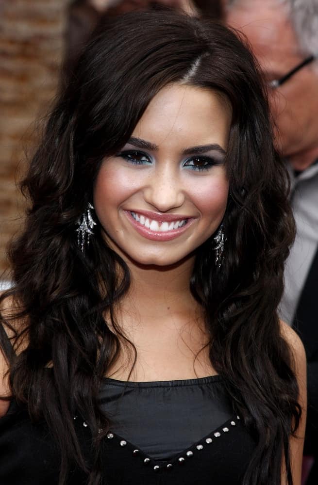 Demi Lovato flashed her brilliant smile that complemented her black outfit and raven loose tousled curly hairstyle with side-swept bangs at the Los Angeles premiere of 'Hannah Montana The Movie' held at the El Capitan Theater in Hollywood on April 4, 2009.