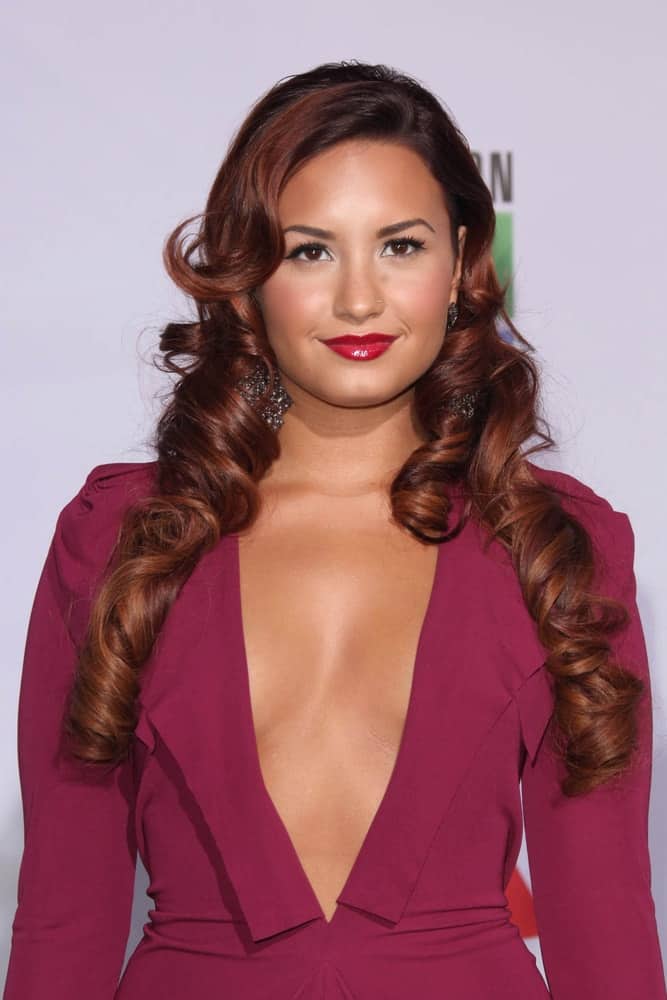 Demi Lovato paired her maroon dress with a unique long and curly highlighted hairstyle with flippy long side-swept bangs at the 12th Annual Latin GRAMMY Awards at Mandalay Bay on November 10, 2011 in Las Vegas, NV.