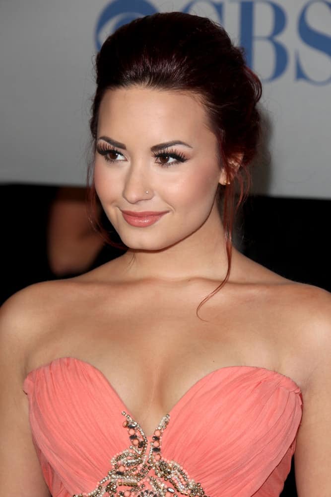 Demi Lovato wore a gorgeous peach strapless dress to match with her loose upstyle that has a dark red tint to its loose tendrils when she arrived at the People's Choice Awards 2012 at Nokia Theater at LA Live on January 11, 2012 in Los Angeles, CA.