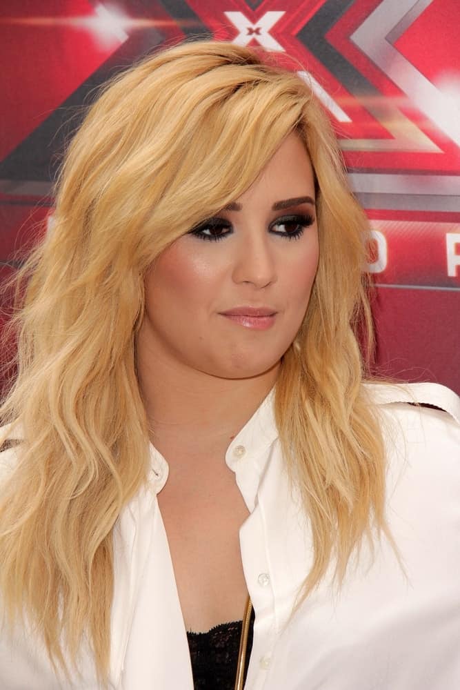 Demi Lovato wore a bright white dress with her bright blond hairstyle that has layers, waves and a slight tousle at the "X-Factor" Season 3 Photo Call at the Galen Center on July 11, 2013 in Los Angeles, CA.