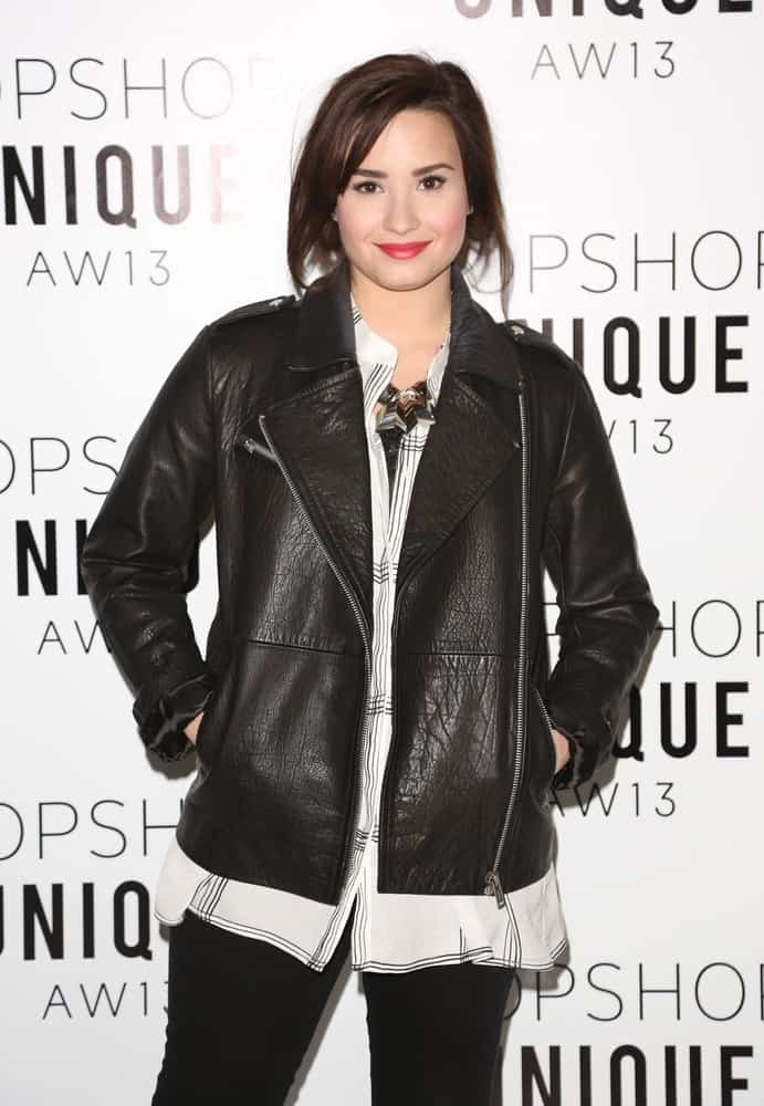 Demi Lovato wore a black leather jacket on her casual outfit to pair with her loose chin-length hairstyle with long side-swept bangs when she arrived at the Unique show as part of the London Fashion Week AW13, Tate Modern in London on February 17, 2013.