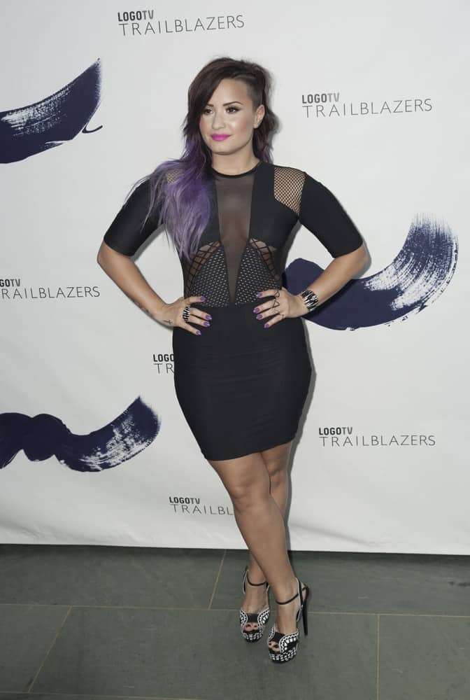 On June 23, 2014, Demi Lovato attended the Logo TV's 'Trailblazers' at the Cathedral of St. John the Divine. She wore a sexy black short dress that flaunted her curves to pair with her long, side-swept and tousled wavy hairstyle with purple highlights and layers.