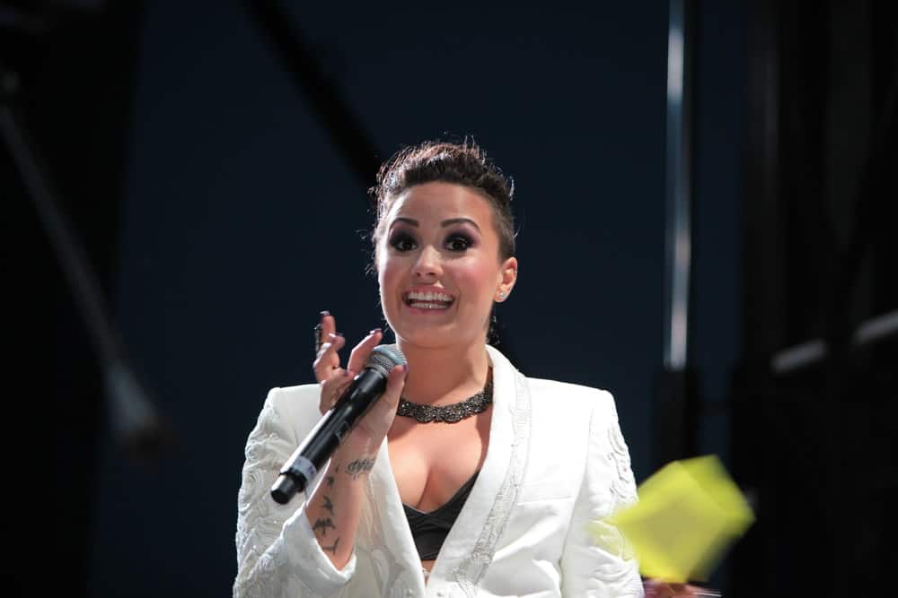 Demi Lovato spoke onstage on June 27,2014 at the second annual Pride Weekend for the 45th anniversary of the Stonewall Riots in Pier 26. She wore a white jacket that paired quite well with her messy upstyle with a shaved side and loose tendrils.