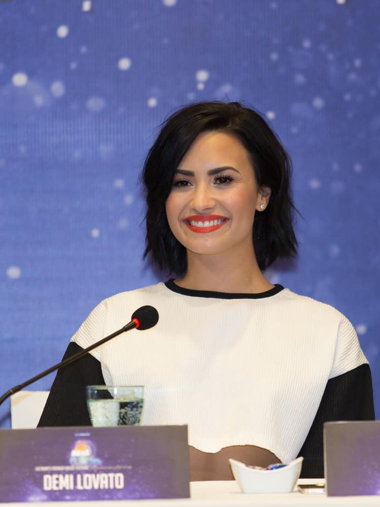 On May 8, 2015, Demi Lovato was at the press conference for the event YAN Beatfest 2015 in Vietnam. She wore a simple black and white casual outfit that went quite well with her short tousled bob hairstyle with layers and side-swept bangs.