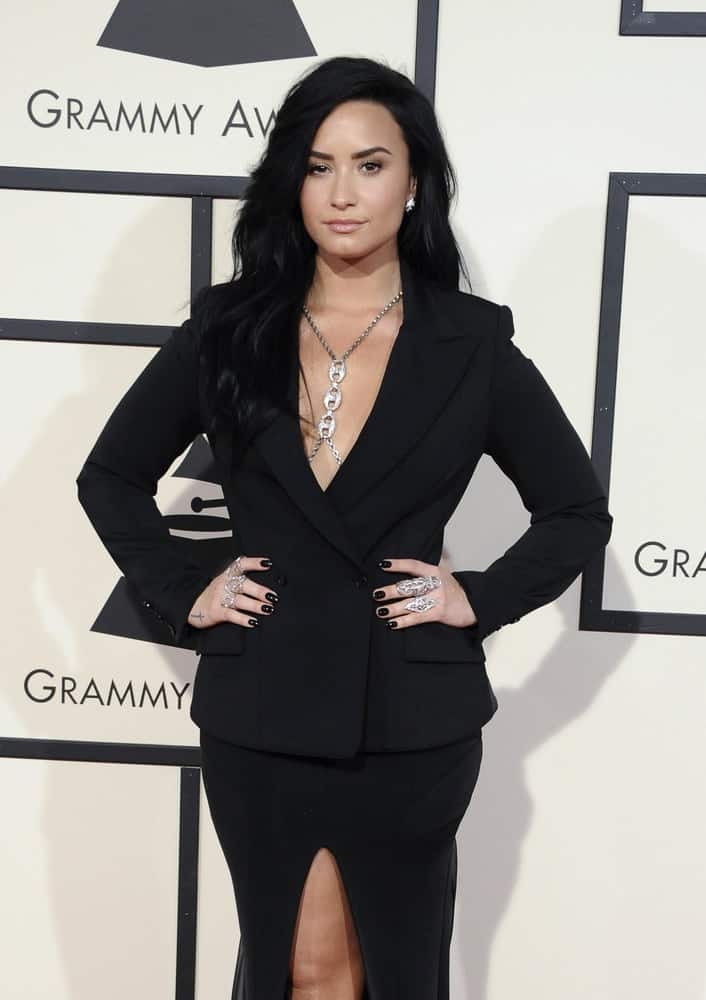 Demi Lovato wore a black smart formal outfit with her long and tousled side-swept raven hairstyle with waves  and layers at the 58th GRAMMY Awards held at the Staples Center in Los Angeles, USA on February 15, 2016.
