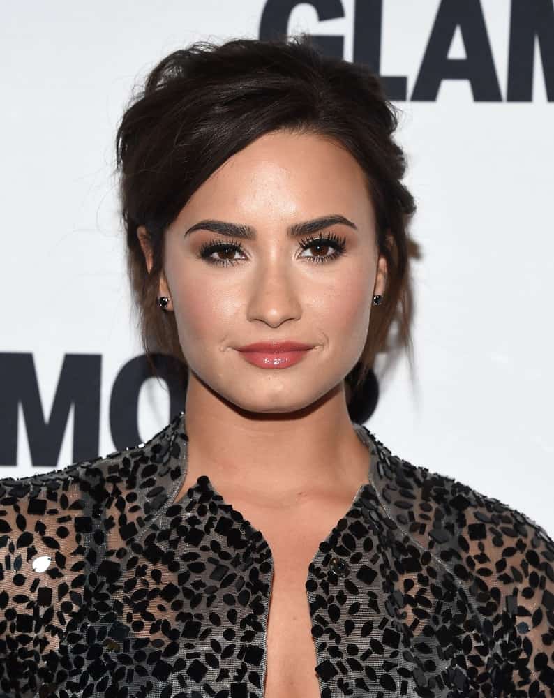 Demi Lovato was quite lovely with her shiny red lips and messy raven upstyle bun hairstyle with side-swept bangs when she arrived at the Glamour Celebrates Women of the Year Awards 2016 on November 14, 2016 in Hollywood, CA.