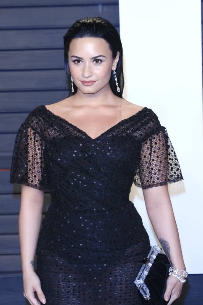 Demi Lovato wore a sexy long black dress that paired quite nicely with her long slicked back raven hairstyle at the 2016 Vanity Fair Oscar Party on February 28, 2016 in Beverly Hills, California.
