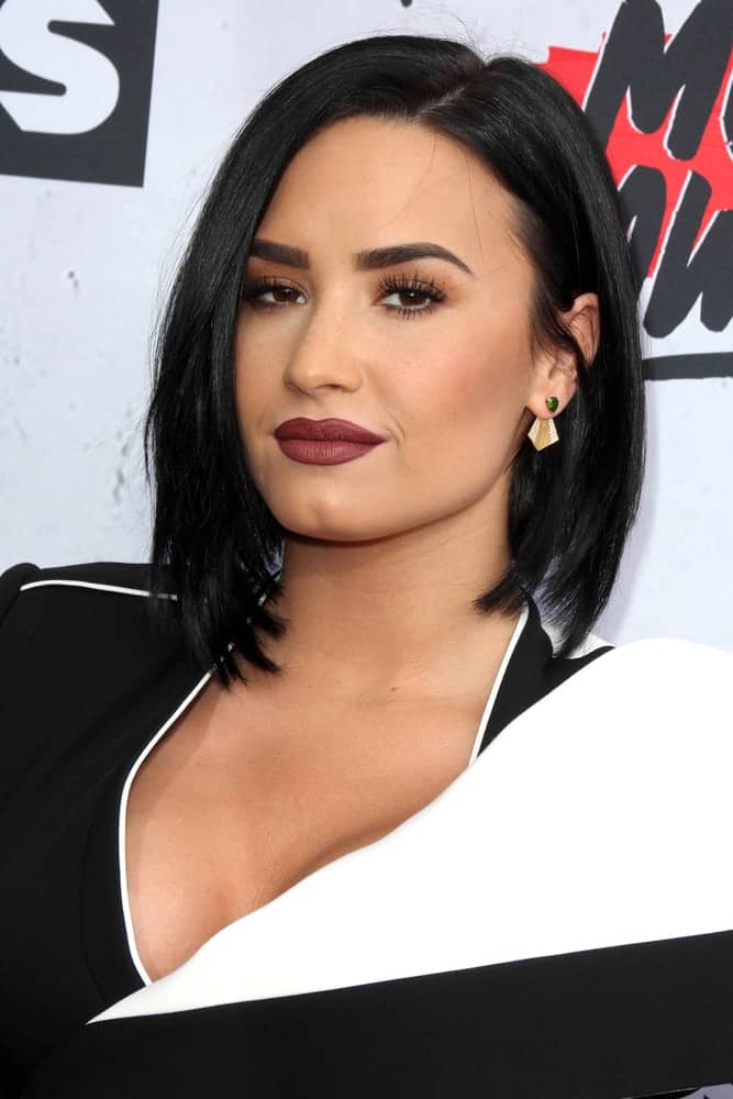Demi Lovato wore a fashionable black and white outfit that she paired with matte red lips and short, straight raven hairstyle at the iHeart Radio Music Awards 2016 Arrivals at the The Forum on April 3, 2016 in Inglewood, CA.
