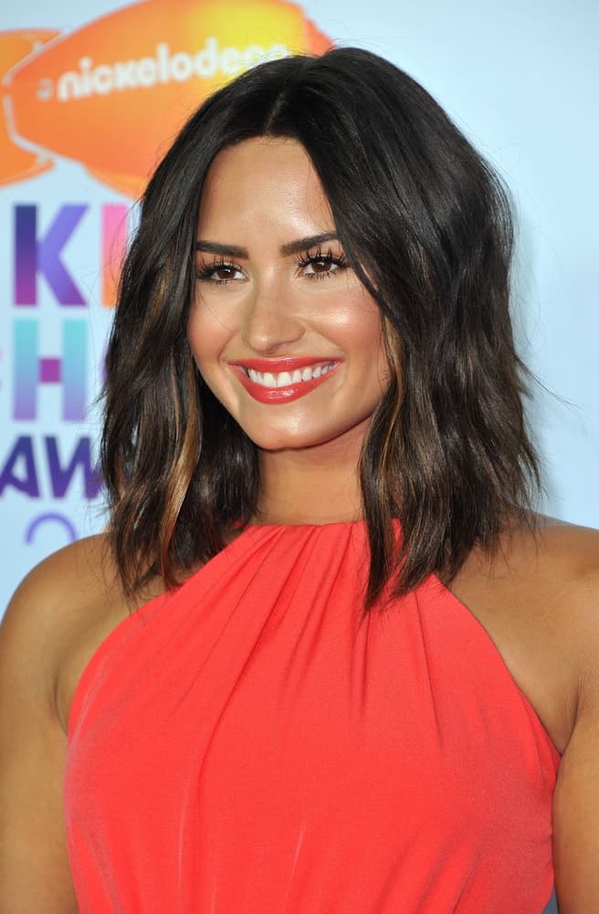 Demi Lovato paired her lovely dress with bold red lips and shoulder-length wavy tousled hairstyle with highlights at the Nickelodeon's 2017 Kids' Choice Awards held at the USC Galen Center in Los Angeles, USA on March 11, 2017.