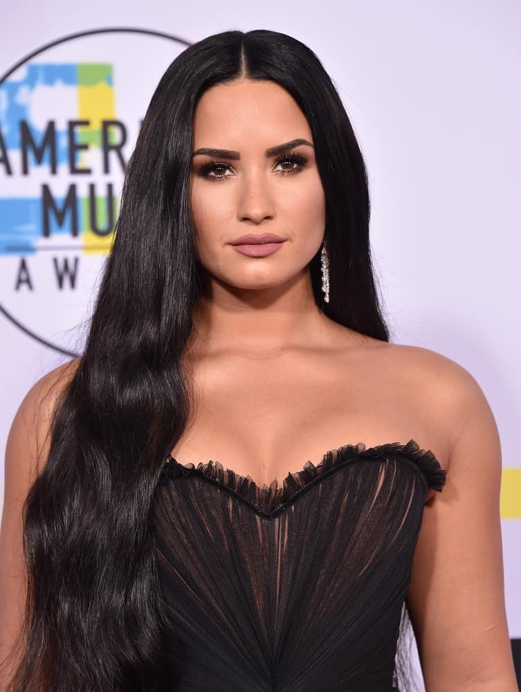 Demi Lovato attended the 2017 American Music Awards on November 19, 2017 in Los Angeles, CA. She wore a sexy strapless black dress to match with her raven long and straight hairstyle with subtle waves at the tips.