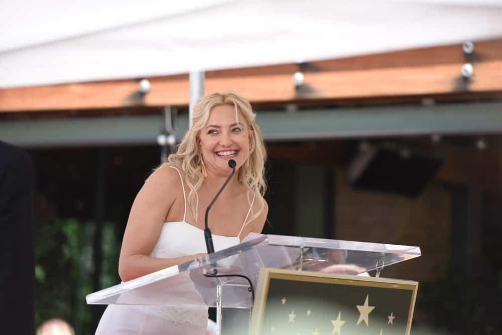 Kate Hudson spoke at the Goldie Hawn & Kurt Russell Hollywood walk of fame Star receiving ceremony at the Hollywood Blvd on May 4, 2017 in Los Angeles, CA. She was charming in her white dress and long, wavy half-up blond hairstyle.
