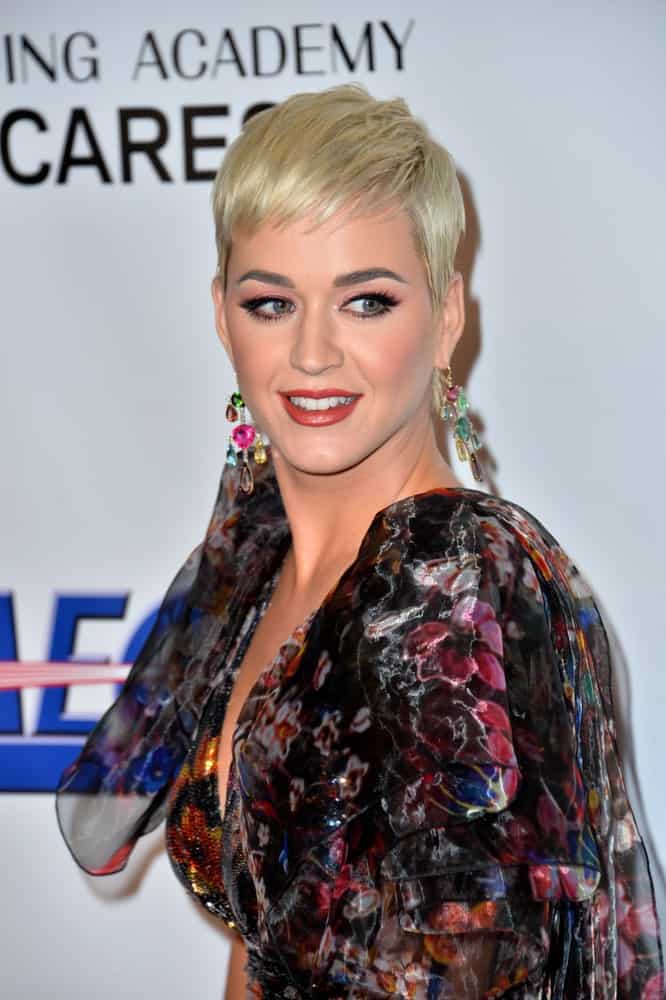 Katy Perry went for a pixie cut emphasizing her colorful chandelier earrings at the 2019 MusiCares Person of the Year Gala honoring Dolly Parton on February 8, 2019.  