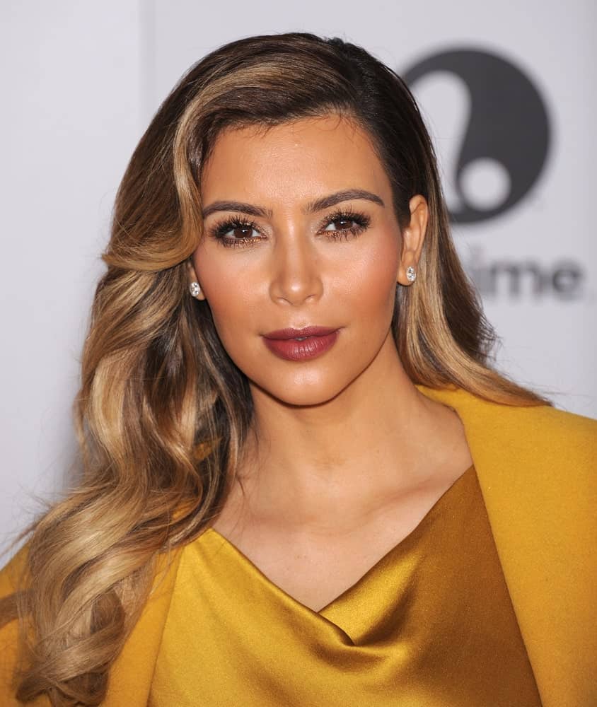 Kim Kardashian displayed her side-swept glam waves in blonde with dark roots at the Entertainment Breakfast 2013 on December 11, 2013. She finished the look with a gold gown and stud earrings.