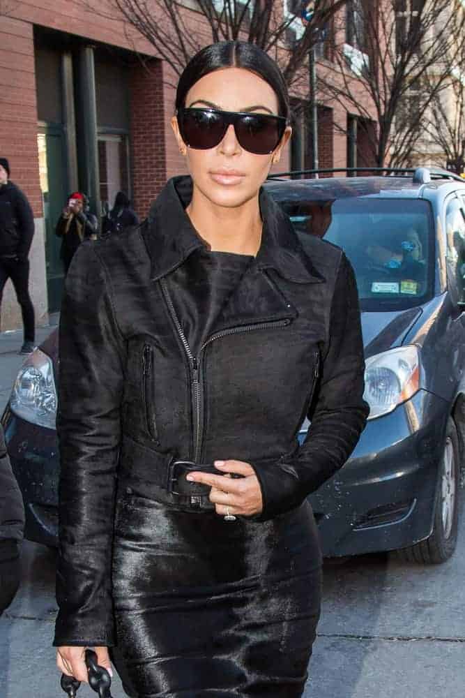 Kim Kardashian was seen wearing an Adidas track jacket under a silk slip dress with her sleek pulled back middle part ponytail while sighting in SoHo.