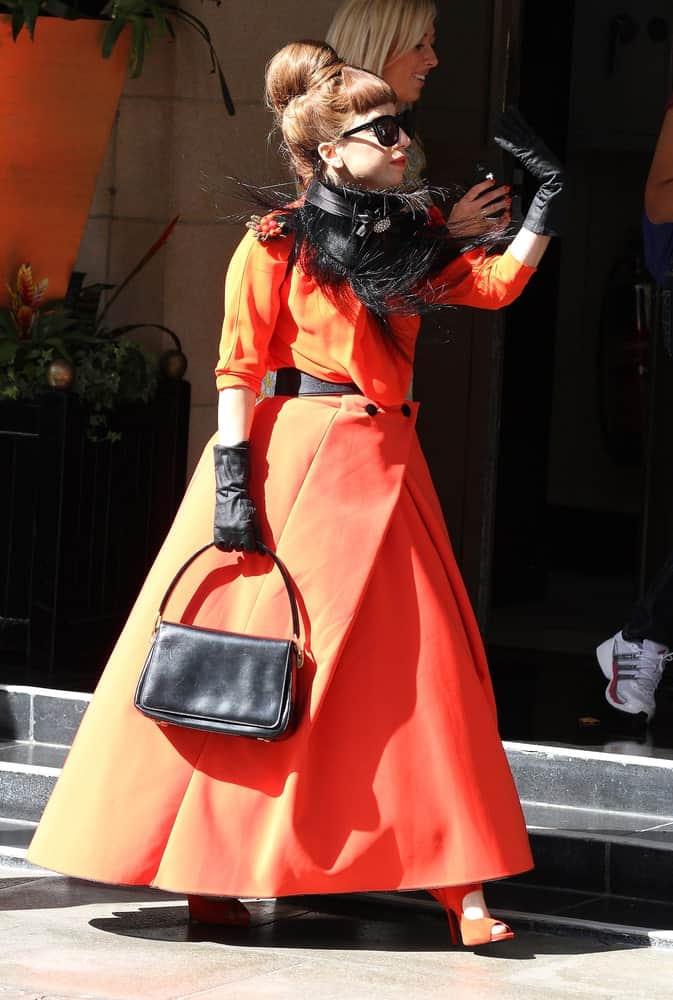 Lady Gaga was seen leaving her hotel on November 9, 2011 in London. She paid homage to Holloween with her pumpkin-colored dress, cool sunglasses and an Audrey Hepburn style hairstyle that has a top knot bun with short blunt bangs.