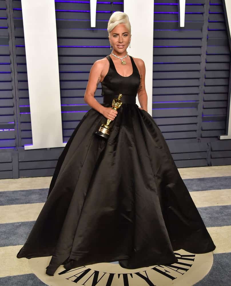 Lady Gaga's gorgeous black ball gown was complemented by her beautiful white blond upstyle with side-swept large curls on top at the Vanity Fair Oscar Party on February 24, 2019 in Beverly Hills, CA.